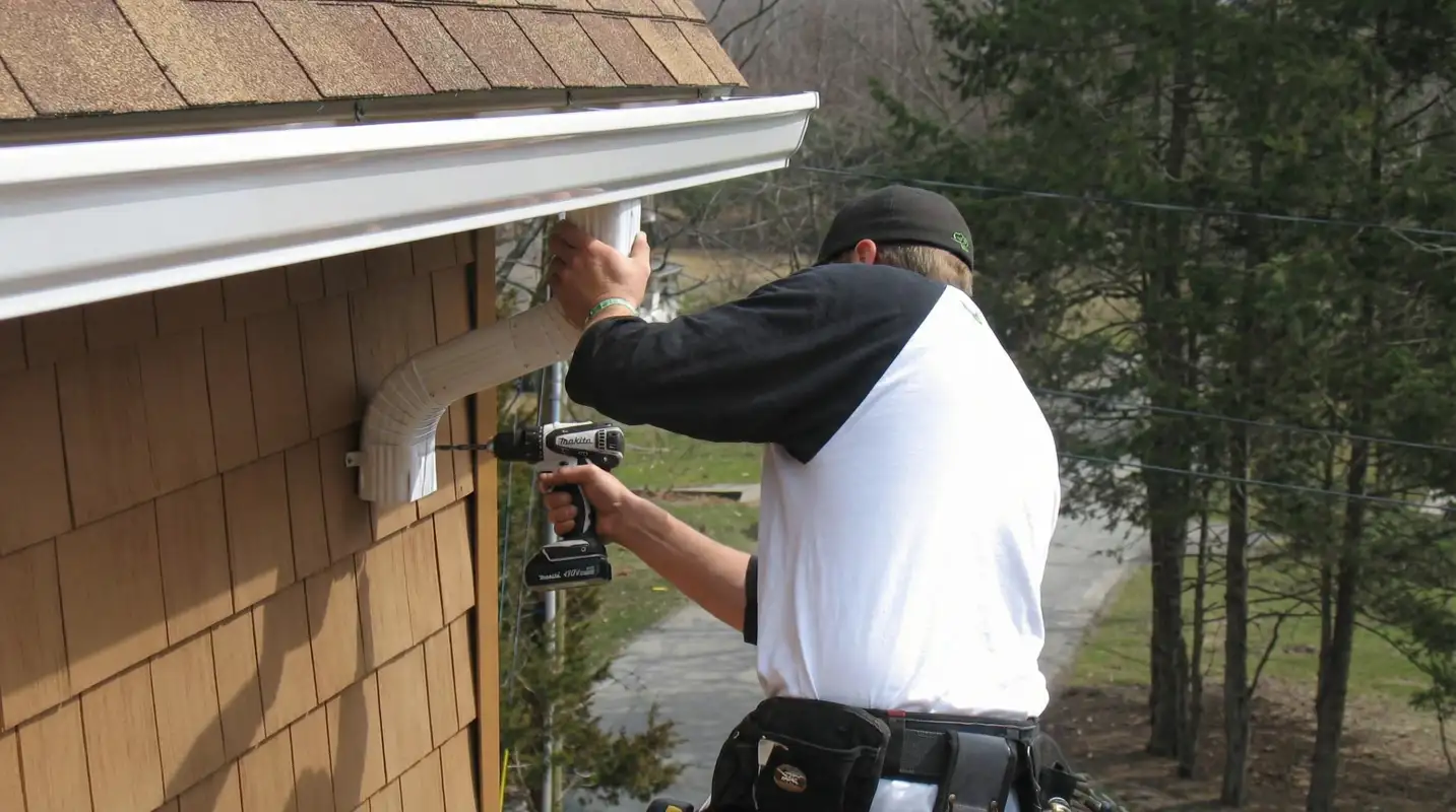Professional contractor installing tan vinyl siding panels on a residential home exterior in Pittsburgh, PA